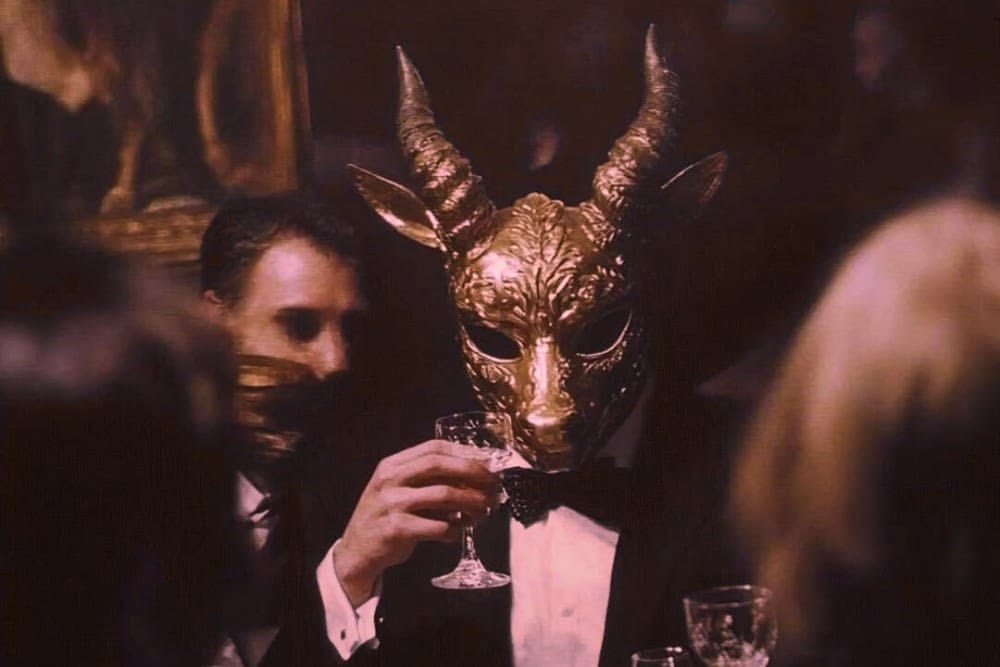 A golden mask raised at the table