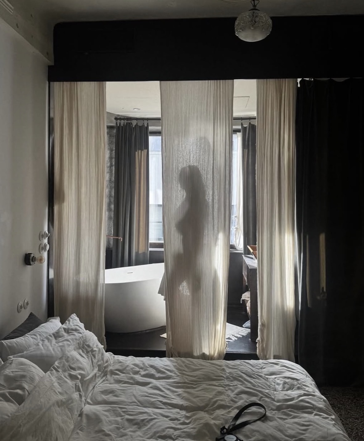 A silhouette behind sheer curtains in a hotel suite